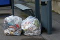 Trash bags placed next to the garbage can at a bus stop