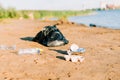 Trash on the beach. Used garbage, plastic wasted water bottle, coffee cup, highlighting the worldwide crisis of plastic