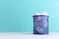 Trash bin with crumpled white paper over blue background Royalty Free Stock Photo