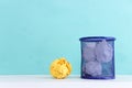 Trash bin with crumpled white and yellow paper over blue background Royalty Free Stock Photo