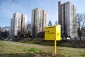 Trash bin for dog refuse stands in city park on green lawn, high rise buildings