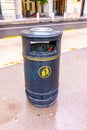 Trash bin with garbage inside in city street. Black recycle bin on the road Royalty Free Stock Photo