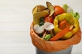 Trash bin with organic waste for composting on white wooden background, closeup Royalty Free Stock Photo