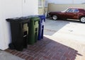 Trash bins for separate garbage disposal, outside the house at the entrance to the garage and a parked red car with the style of t