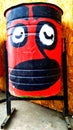 Trash can with graffiti in the form of eyes, nose and mouth