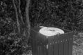 Trash can in the park surrounded by trees.