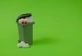 A trash can, a white heart with eyes looking at a broken heart at the bottom on a bright green background. Text space. Royalty Free Stock Photo