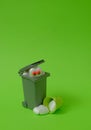 A trash can, a white heart with eyes looking at a broken heart at the bottom and a small green bucket on a bright green background Royalty Free Stock Photo