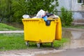 Trash cans are full. Yellow trash bin, plastic trash can.