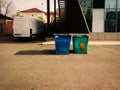 trash dumpsters rusty. Dustbins full of litter near office building with new commercial van on background