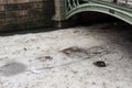 Trash, empty bottles and cans on the partly melted ice in a canal