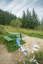 Trash and garbage near bench in mountain forest landscape, nature