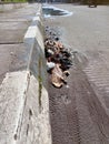 trash on the side of the road near the sidewalk and there are puddles of water on the road Royalty Free Stock Photo