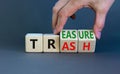 Trash to treasure symbol. Businessman turns cubes and changes the word trash to treasure. Beautiful grey table, grey background.