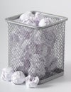 A trashcan full of crumpled paper on white background close up