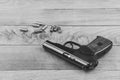 Traumatic pistol with bullets and cartridge on the wooden surface, black and white Royalty Free Stock Photo