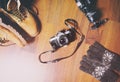 Travel accessories set on wooden background: hiking leather boots, vintage camera, tripod .