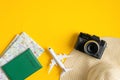 Travel accessories on yellow background. Flat lay vintage camera, beach hat, map, passport, airplane. Top view with copy space.