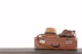 Travel and adventure concept. Vintage brown suitcase with fedora hat, bullwhip and shoes against white isolated background