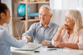 Travel agent at office sitting shaking hands with senior client cheerful Royalty Free Stock Photo