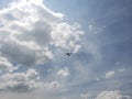 blue sky with white clouds and the silhouette of an airplane