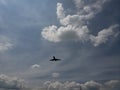 blue sky with white clouds and the silhouette of a plane