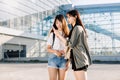 Travel and airport flights concept. Two beautiful young asian women in stylish clothes, using smartphone for check-in on