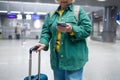 Travel, airport senior 60s woman in comfy casual outfit going vacation alone, holding a smartphone and booking cheap Royalty Free Stock Photo