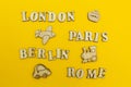 Travel around Europe, the names of cities: `Paris, London, Berlin, Rome` on a yellow background. Wooden figures of an airplane,