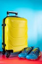 Travel bag on wheels. A bright travel suitcase and sports shoes. Yellow bag on wheels Royalty Free Stock Photo