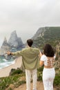 Travel blog concept. Lady making photo on cellphone of european man standing back to her, coastline view, vertical shot Royalty Free Stock Photo