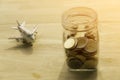 Travel money savings in a glass jar and put on wooden present budgets in holiday.