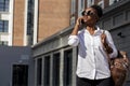 African american woman with backpack walking outdoor and talking on mobile phone Royalty Free Stock Photo