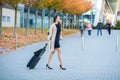 Travel. Business Woman in airport talking on the smartphone while walking with hand luggage in airport going to gate