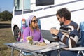Travel and camping people lifestyle outdoor leisure. Couple with adult man and woman enjoying time together outside a camper van.