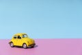 Travel car concept background. Yellow toy car on empty minimal pastel background. Driving, riding, road idea Royalty Free Stock Photo