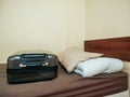 Travel case on a small simple bed. Concept cheap and budget accommodation for rent