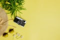 Travel concept with camera, green leaves, sun glasses and hat over the yellow background. Royalty Free Stock Photo