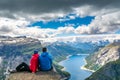 Travel concept. The couple sitting on a cliff over a lake, Trolltunga, Norway. Amazing nature view. Artistic picture. Beauty world Royalty Free Stock Photo