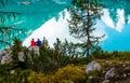 Travel concept. The couple sitting on the shore of famous lake Sorapis with turquoise water. Very popular location for photography