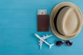 Travel Concept : Flat lay of straw hat, passport with money, plane model and sunglasses, on blue wooden background, with copy spa