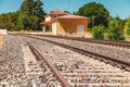travel concept image with train tracks in the foreground and an empty train station out of focus in the background Royalty Free Stock Photo