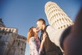 Travel concept. Loving couple takes selfie photo on stick and camera against background of leaning Tower Pisa, Italy. Royalty Free Stock Photo