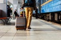 Travel concept. Men wear sneakers shoes and yellow pants travel with brown luggage and backpack on the train station. Sunny day. Royalty Free Stock Photo