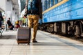 Travel concept. Men wear sneakers shoes and yellow pants travel with brown luggage and backpack on the train station. Sunny day. Royalty Free Stock Photo