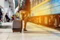 Travel concept. Men wear sneakers shoes and yellow pants travel with brown luggage and backpack on the train station. Sunny day. Royalty Free Stock Photo