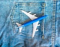 Travel concept passenger plane in jeans pocket. Top view aircraft model in blue on denim blue trousers