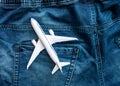 Travel concept passenger plane in jeans pocket. Top view aircraft model white on dark denim blue trousers