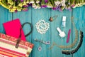 straw bag, colorful flowers, cosmetics makeup, notepad, bijou and essentials on blue wooden background