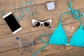 blue swimsuit, smart phone, sunglasses, headphones, gift box and shopping carts on brown wooden table